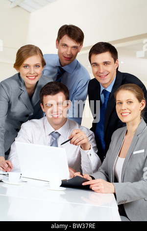 Portrait of several successful co-workers looking at camera with smiles at workplace Stock Photo