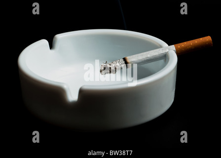 burning cigarette in the ashtray white on black background Stock Photo