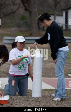 Female college students belonging to Filipino-American campus group use brushes to paint pole at a city park Stock Photo