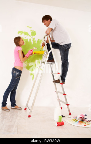 Affectionate couple helping each other to paint walls in new house Stock Photo