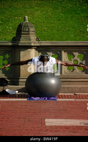 A physically fit African American young man wearing headphones exercises with an exercise in Central Park, New York City. Stock Photo