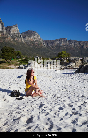 Woman on Camps Bay beach with Twelve Apostles in background, Cape Town, Western Cape, South Africa Stock Photo