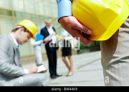Close-up of builder holding helmet with construction at background Stock Photo