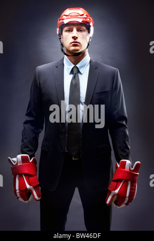 Portrait of young businessman in suit and hockey helmet and gloves Stock Photo