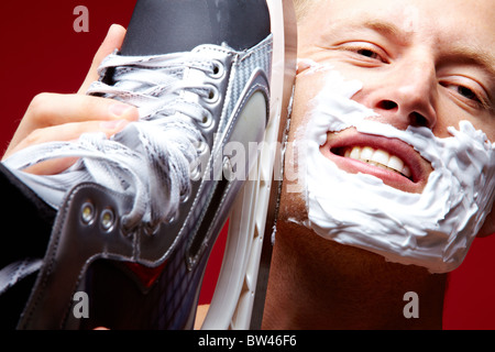 Portrait of young man with foam on face shaving with skate razor Stock Photo