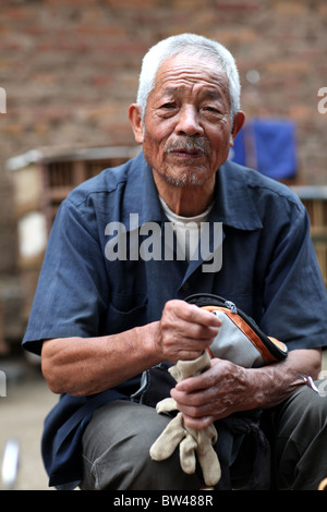 A local man selling small birds for pets, also considered lucky, on the streets in Kunming, China. Stock Photo
