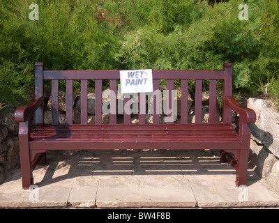 Notice warning of wet paint on a park bench in a park in Sidmouth devon Stock Photo