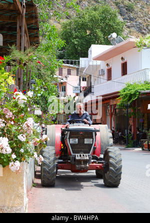 Busy Greek farmer drives his tractor through the Spili village on May 16, 2010 in Spili village, Crete, Greece. Stock Photo