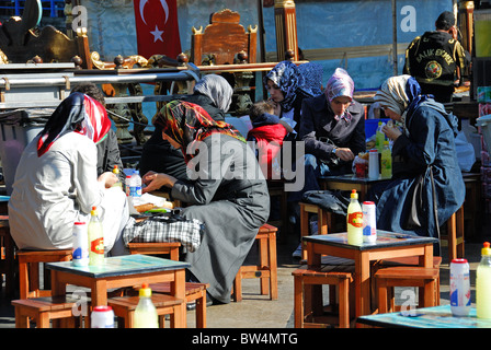 ISTANBUL, TURKEY. Young Turkish women eating balik ekmek (fish sandwiches) by the Golden Horn in Eminonu district. Stock Photo