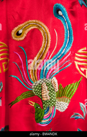 Colourful red Chinese embroidered silk garment depicting a phoenix bird, for sale, China Stock Photo