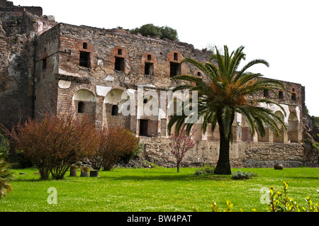 The ruins of a building still showing decorative plaster facing, abutting the city walls and in front of the gardens of Pompeii Stock Photo