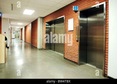 Freight and regular steel door elevators with signs in an empty hallway of modern building. Can be office, school, hospital. Stock Photo