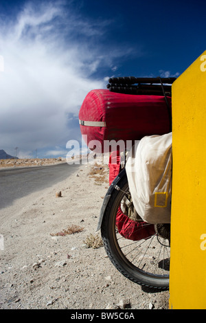A touring bicycle parked against a yellow road sign on the Leh-Manali mountain highway Stock Photo