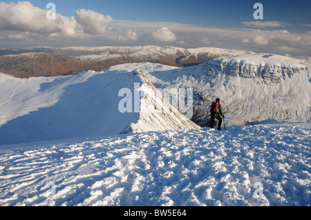 Walker on Helvellyn looking out over Striding Edge towards St Sunday Crag. Winter mountain view in the English Lake District Stock Photo
