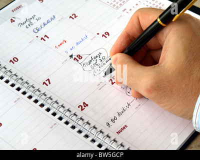 Man filling out  monthly planner on the table Stock Photo