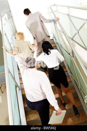 Back view of group of business people going upstairs in office building Stock Photo