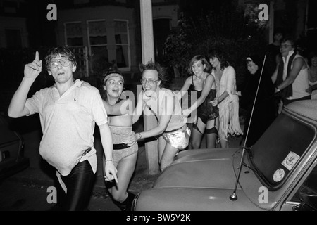 Middle class fancy dress party Christmas party doing the Conga line dance in the street. Wimbledon SW19  London England UK 1980s 1983 HOMER SYKES Stock Photo