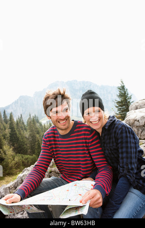 Couple with map sitting on rock Stock Photo