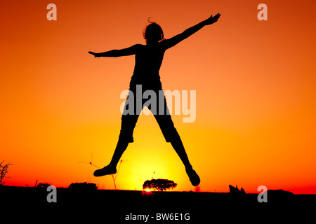 Silhouette of a young woman jumping at the sunset Stock Photo