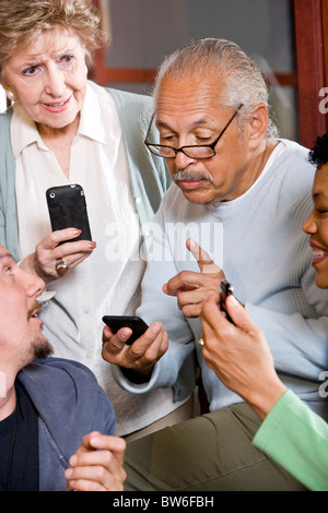Senior Hispanic man in group asking question about mobile phone Stock Photo