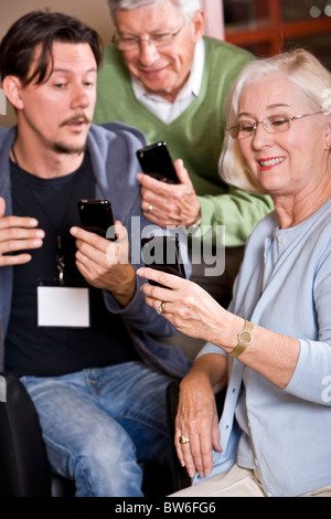 Man helping senior couple with their smart phones Stock Photo