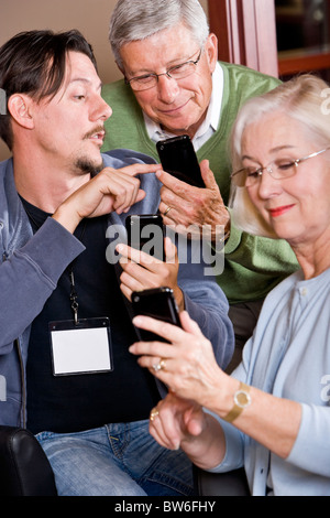 Man helping senior couple use their smart phones Stock Photo