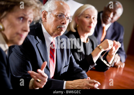 Hispanic man listening in multi-ethnic senior management meeting Stock Photo