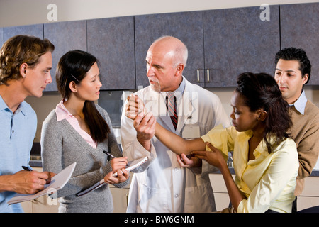 Medical school professor teaching students, examining patient's arm Stock Photo