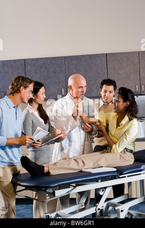 Students learning from medical school professor, practice on patient Stock Photo