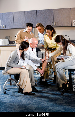 Medical school professor teaching students, examining patient's leg Stock Photo