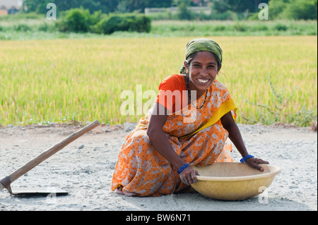 Indian woman road worker picking up stones by hand off a newly laid road before the top surface is applied. Andhra Pradesh, India
