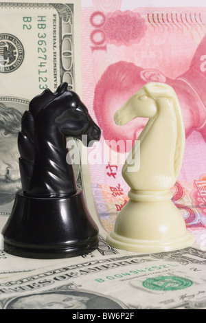 Currency war - Opposing black and white knights standing on US dollars and Chinese Yuan Stock Photo