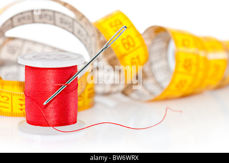 Colored bobbin for sewing and measuring tape over white Stock Photo