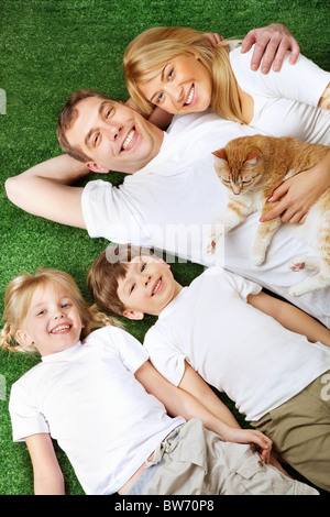 Above view of family members with pet lying on green grass and having rest Stock Photo