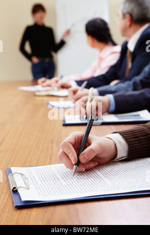 Row of business people making notes during presentation Stock Photo