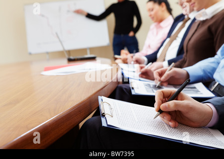 Close-up of businesspeople hands with documents writing at lecture Stock Photo