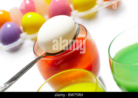 Red color easter egg near the ceramic bowl filled by colored easter ...
