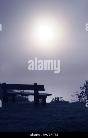 Empty bench looking across a misty expanse Stock Photo