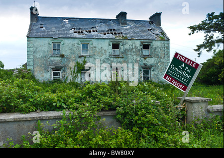 Derelict period house with for sale estate agent auctioneer board in Moyasta, County Clare, Ireland Stock Photo