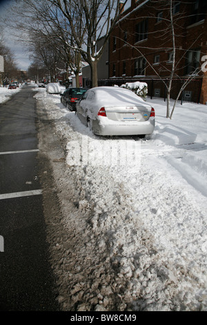 snow surrounds cars parked on a plowed city side street in winter Stock Photo