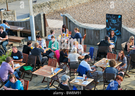 Peolpe relaxing with drinks at beachfront bar/cafe on Brighton beach, East Sussex, UK Stock Photo