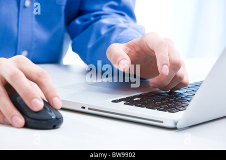Close-up of male hands on mouse and over black keyboard of laptop during typing Stock Photo