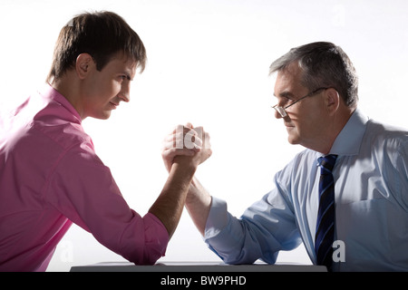 Profiles of two partners looking at each other while arm wrestling Stock Photo