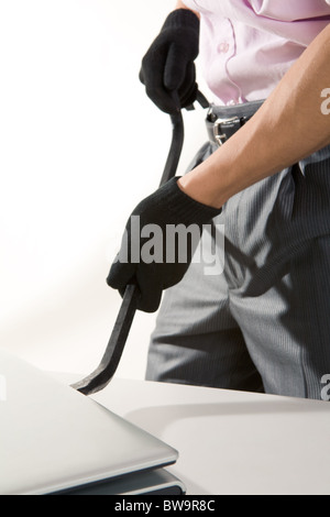 Image of male wearing black gloves and opening laptop with metallic tool Stock Photo