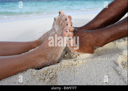 Close-up of feet of a dark skinned couple, Desroches Island, Seychelles Stock Photo