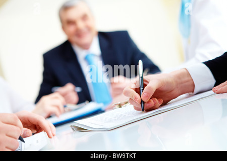 Close-up of secretary hands over document with her boss on background Stock Photo