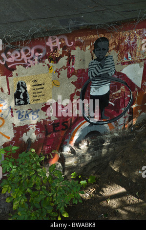 Stencils of child and wall paper graffito of a woman on a wall near the Flutgragen in Berlin (Alt-Treptow, Kreuzberg), Germany Stock Photo