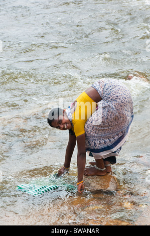 Smiling happy Indian teenage girl washing clothes by hand in the river. Andhra Pradesh, India Stock Photo