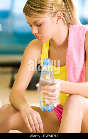 Photo of exerted female having a drink of water after difficult exercises Stock Photo