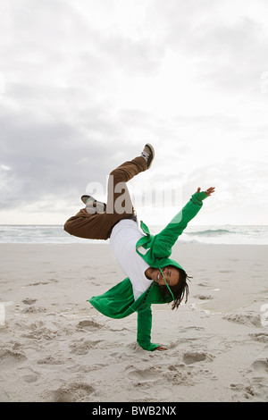 Young man doing cartwheels on beach Stock Photo